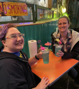 Two people drinking fancy blue cocktails with flamingo and umbrella straws. 